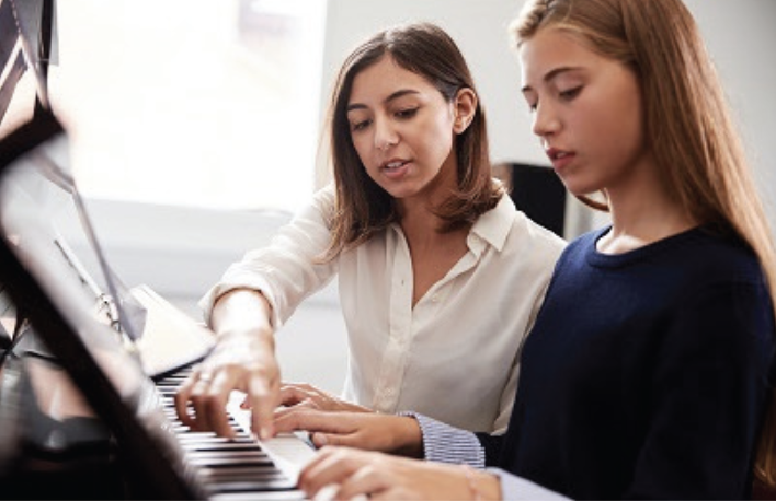 piano teacher and student sitting at a piano